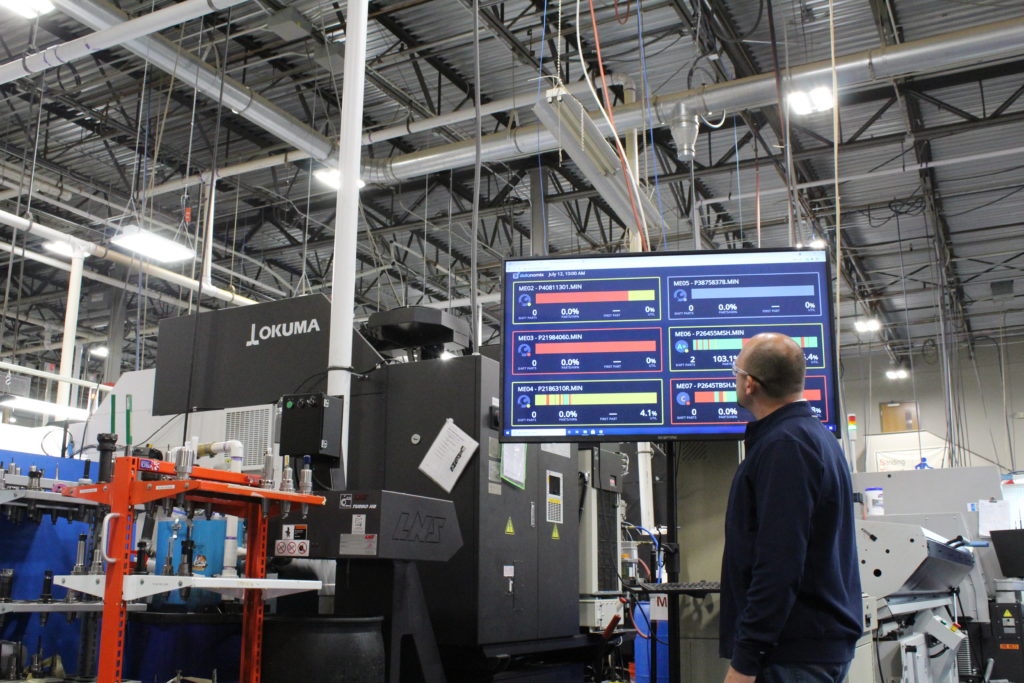 CNC Machine operators looking at Datanomix data displayed on the shop floor.